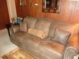 Over-stuffed brown leather sofa (has matching chair and ottoman), throw pillow, leather-framed mirror, small oriental-style rug