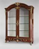 Lot# 1043 A Regence style gilt bronze-mounted parquetry vitrine Second half 19th century, two mounts incised ''PA'', another stamped ''Patry'' and with numbers, of kingwood and rosewood with oak secondary wood, the arched cornice with ovolo molding centered by a mask and acanthus clasp, over a pair of arched doors inset with beveled glass enclosing a silk-lined interior fitted with glass shelves, flanked by Bacchic mask-headed uprights with bronze-inlaid flutes, over a shaped apron centered by an espagnolette, enclosing a long drawer, raised on foliate scrolled feet, electrified, with key, 9'1'' H x 6'9'' W x 2'5'' D, est: $40,000/60,000
