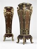 Lot# 1045 A pair of gilt bronze-mounted 'Boulle' marquetry pedestals Late 20th century, each with a square inset vert maurin marble top within a molded frieze centering a rocaille clasp to each side, over a tapering body mounted to the upper angles with male and female caryatid chutes, each side inlaid with an elongated cartouche-shaped brass and tortoiseshell panel of foliage within a foliate scroll molding, on a square base raised on short acanthus-cast legs on scrolled feet, 2 pcs, each 59'' H x 18'' W x 18'' D, est: $3000/5000