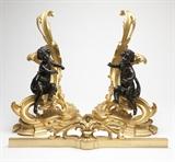 Lot# 1048 A pair of Rococo style gilt & patinated bronze chenets Late 19th / 20th century, each with a cherub perched on a rocaille, scroll and foliate-cast base, together with fender, 3 pcs, each 21.5'' H x 15.5'' W x 8'' D, est: $2500/3500