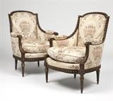 Lot# 1055 A pair of Louis XVI style bergeres Early 20th century, the partially gilt frames carved with spiral ribbons and foliage, the arched backs, closed arms, elbow rests and down-filled seat cushions covered with later damask fabric in a floral pattern on a cream-colored ground, 2 pcs, 37.5'' H x 26'' W x 27.25'' D, est: $1500/2000