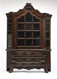 Lot# 1074 A diminutive Dutch burr-walnut & oak cabinet
 
19th century, the arched molded crested cornice above an arched glazed door flanked by angled glazed side panels enclosing two removable wooden shelves, over three long drawers flanked by angled panels, over a shaped apron on ball-and-claw feet, with key, 39.25'' H x 28'' W x 7.75'' D, est: $1500/2000