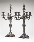 Lot# 1099 A pair of Old Sheffield Plate four-light candelabra Early 19th century, mark of W. Garnett, Bridge Houses, Sheffield, of Rococo style, each with a domed foot and baluster-form stem issuing a central light with a removable en flambeau finial, and three 'S'-form arms with urn-form sockets and removable nozzles, cast all over with rocaille, 'C"-scrolls and foliage, 2 pcs, each 28.25'' H x 16'' Dia., est: $800/1200