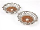 Lot# 1101 A pair of Victorian silver-plated wine coasters
 
1858, Birmingham, with maker's marks of Elkington, Mason & Co., each with a circular grapevine rim over incurved pierced latticework walls on a wood-inset base, 2 pcs, each 2'' H x 7.5'' Dia., est: $600/900