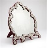 Lot# 1104 A Rococo style sterling silver-mounted table mirror
 
1903, London, maker's mark of William Comyns & Sons, the cartouche-shaped beveled mirror plate within a floral, rocaille and ''C''-scroll surround mounted to a burgundy cloth-covered easel-back stand, 18.25'' H x 16'' W x 11.75'' D, est: $600/800