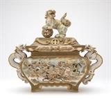 Lot# 1113 A Japanese Satsuma koro / censer Meiji era (1868 - 1912), signed to underside, the rectangular domed pierced cover surmounted by a dog-form finial surrounded by a relief-molded dragon, the bombe body decorated to all four sides with a battle scene with figures and horses, flanked by dragon-form handles and raised on leaf-shaped feet, the whole richly polychrome-enameled and gilt, 12.25'' H x 14.5'' W x 7'' D, est: $1000/2000