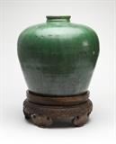 Lot# 1121 A large Chinese earthenware storage jar
 
18th or 19th century, unmarked, the short circular neck over a high-shouldered body, covered with camellia leaf-green glaze, with a carved wooden base, 18'' H x 19'' Dia., est: $1000/1500