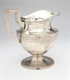 Lot# 1138 A Gorham sterling silver water pitcher Late 19th / early 20th century, Providence, RI, with lion-anchor-''G'' mark, further marked ''Sterling'' and stamped ''1351L'', the wide circular rim and spout over an urn-form body issuing a squared handle, on a circular foot, hand hammered all over and decorated with scrolling foliate bands and medallions with interlaced borders, 9.75'' H x 9.75'' W x 6.75'' D, 34.4 oz troy approximately, est: $1000/1500