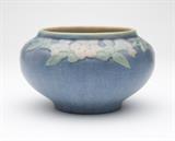 Lot# 1158 An Anna Simpson / Newcomb College pottery vase
 
1923, with incised ''NC'' monogram, signed ''AFS'' (Anna Frances Simpson d. 1930), impressed style number 257, impressed registration number NK85, of compressed globular form with a short neck and foot, the exterior glazed in matte blue with a pale pink and green relief-molded band of flowers and foliage to the shoulder, the interior buff-colored , 4.25'' H x 7.25'' Dia., est: $1000/2000