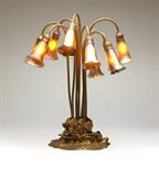 Lot# 1162 A Tiffany Studios Lily ten-light table lamp Circa 1910, the base stamped ''Tiffany Studios / New York / 381'', the gilt bronze foliate cluster base issuing ten stems terminating in irridescent Favrile glass bud-form shades, nine signed ''LCT'' and one signed ''LCT / Favrile'', electrified, the switch marked ''The Hart & Hegeman Mfg. Co. / Hart Switch'', 20.75'' H x 18'' Dia., est: $15,000/18,000