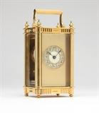 Lot# 1183 A Joseph Eastman carriage clock Circa 1880, the white circular dial with black Arabic hours with outer cartouche pierced coverlet, within a gold-plated case with beveled glass panels and finials to each of the four corners, stamped to backplate ''2747 C'', with key , 6.25'' H x 3.125'' W x 2.5'' D, est: $500/800