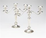 Lot# 1191 A pair of Gorham sterling silver candelabra Mid 20th century, Providence, RI, with maker's marks, further marked ''Sterling'' and ''890'', and with manufacturer's paper sticker, each with a tapering stem surmounted by a central light issuing flanking S-form candlearms, the circular foot and urn-form sockets with raised floral decoration, convertible to candlesticks, weighted, 2 pcs, each 11'' H x 11.5'' W x 4'' D, total gross weight 54 oz troy approximately, est: $500/700