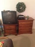 chest of drawers with pull out and bed side table with tv on top of it