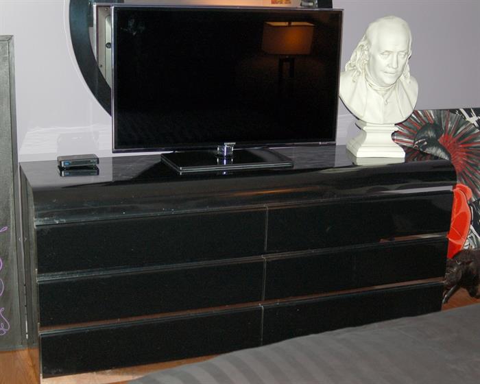 Modern contemporary black wide dresser with round mirror. 40" Samsung flat widescreen TV. Large president busts.