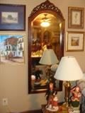 Gorgeous framed mirror surrounded by lovely prints, figurines and table lamp
