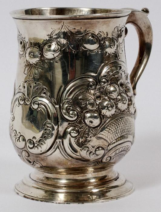 Lot#1020, GEORGE III STERLING TANKARD, LONDON, 1772-73, H 5"Repousse floral basket and scroll motifs, with a scroll handle.  Hallmarks include a lion passant, crowned leopard, date letter R, and partially rubbed maker's mark.  Weighs approximately 11.5 troy oz.