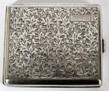Lot#1242, .950 SILVER CIGARETTE CASE, C. 1940, W 3", L 3 1/2"Decorated with incised scrolling foliate motif at the exterior, having a push button opening to an interior fitted at both sides with link chains. Marked "950 Silver". Measuring L. 3 1/2" x 3", with a total approximate weight of 3.66 tr.oz.