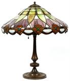Lot#2, HANDEL TABLE LAMP, H 22", DIA 19"The round shade comprises slag glass panels of green, caramel, purple, white and brown, raised on a bronze base with an applied Handel black label to the green felt at the underside of the base (see additional photo); no other apparent markings.
