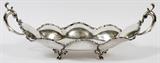 Lot#17, JUVENTO LOPEZ REYES, STERLING FOOTED TRAY, 20TH C., L 23"Sterling double handled tray in a lobed form, raised on four feet, with scrolling foliate motif at the edges. Made by Juvento Lopez Reyes, Mexico City, 20th Century. Measuring H. 8 1/4" x 23 1/4" x 12 3/4", with a total approximate weight of 73.65 tr.oz.