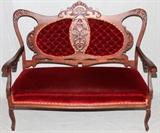 Lot#55, ART NOUVEAU INFLUENCE MAHOGANY SETTEE, H 40", L 49"Having shell from and leaf carving on the back with burgundy velvet upholstery.