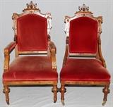 Lot#56, EASTLAKE STYLE CARVED GENTLEMAN'S AND LADY'S CHAIRS, TWO//The gentleman's arm chair, H 44", features carving on the back frame, crest and arms while the lady's side chair, H 43", has a carved back frame, crest, both with red velvet upholstery; Both with brass casters.