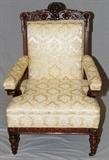 Lot#58, CARVED MAHOGANY OPEN ARM CHAIR, H 39", L 27"Having ivory brocade upholstery, carved back crest and frame, upholstered armrests and carved armrest supports. Turned and fluted front legs, metal casters.