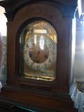 German walnut case mantel clock. Arched framed door with beveled glass inlaid with with leaf design. Stepped base. Engraved brass dial. Movement marked Unghans J (star) B06