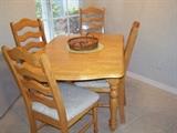 All wood kitchen table with four chairs.  Features a drop down on each end to make it square, and an extra leaf (not shown).