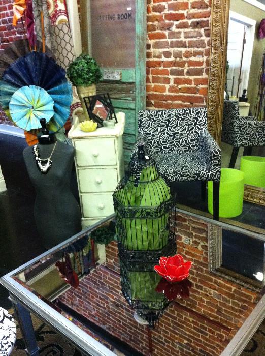 square glass top table; small 3-drawer chest; mannequins; modern style chair; decorative items