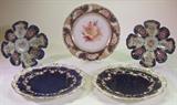Selection from cobalt decorated porcelain items. Front row-pair of Adderley, England, cobalt decorative plates, with gold scroll work border and hand-painted garland of flowers and enameled jewels. Back row-pair of decorative hand-painted floral plates, in an 8-well oyster plate form. Center-hand-painted floral decorative plate with reticulated border by Nymphenburg, Germany.