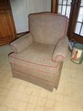 A comfortable tan armchair with a red border