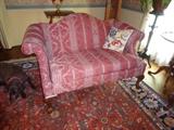 A small formal loveseat with cherry finish on the legs. 