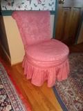 A pink upholstered chair with a unique shape.