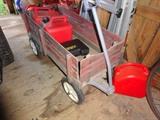 A red wheelbarrow and three red gas cans