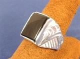 Pictured is a man's sterling silver ring set with a rectangular black onyx. We manufacture this ring by hand right here in Texas; we make it from injecting the wax model, to investing and casting the ring, to hand finishing and hand setting the stone ourselves. We ARE the manufacturer! The style of the ring has a very 1930's look. The ring is a nice weight; it weighs (with the stone) over 11 grams. The ring is made in a size 9.