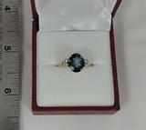 Here is an interesting ladies' ring made in 14 karat yellow gold. Made about 1960, it came to us with a badly broken center stone. We furnished a new London blue topaz for the center, set it into the ring, and completely refinished it. There are two white stones on each side of the blue topaz which are not diamonds. Size six.