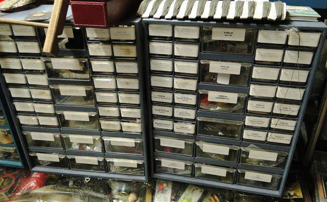 Display cabinets full of repair parts of fishing reels - sold by the lot.