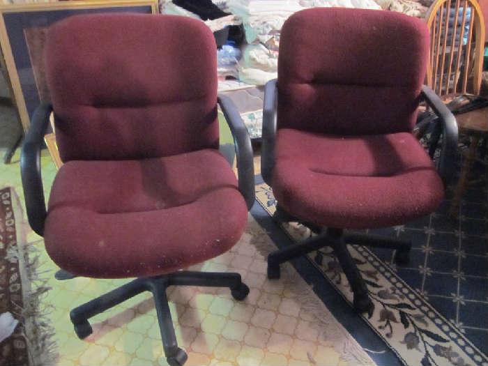 Two Burgundy desk chairs, they swivel, roll and had pheumatic height adjustment.