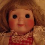 Precious up close of the doll in gingham dress and pinafore