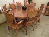 Oak kitchen pedestal table and eight pressed back chairs.