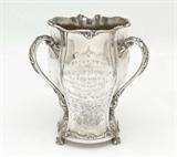 Lot 1002:  IMPORTANT TENNESSEE STERLING PRESENTATION LOVING CUP: Tri handled sterling silver loving cup by Gorham presented to the wife of the Governor of Tennessee in 1900. Presentation reads '' Presented to Mrs. Benton McMillin by the Retail Merchants Association of Nashville Tennessee. In grateful acknowledgment and appreciation of her gracious courtesy and distinguished ability as Chairman of the Ladies Flower Committee of the May Festival of 1900''. Etched scene of horse and carriage in another panel, large flourishing monogram in a 3rd panel. Marked on base with Gorham marks, Sterling, A711, 5 Pint. On 3 claw and ball feet. Overall measures 9 1/4'' h. x 8'', approx. 43.8 troy oz.
CONDITION: Several minor dings, one larger ding at monogram, scratches from cleaning.
