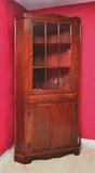 Lot 1094:  MAHOGANY CORNER CABINET: 9 light top door with 2 shelves over single drawer over 2 blind front doors with single shelf, shaped skirt. 83'' h. x 42'' x 23''.
