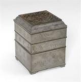 Lot 1181:  CHINESE SQUARE PEWTER INCENSE CLOCK: In 3 levels with reticulated lid, lower level with removable tray. The clock bodies are specialized censers that hold a measured amount of incense to accurately measures minutes, hours or days. Decorated with foliate motif, symbols. Marked on base. Overall measures 4 5/8'' h. x 3 3/4'' x 3 3/4''.
CONDITION: Several splits at corners.