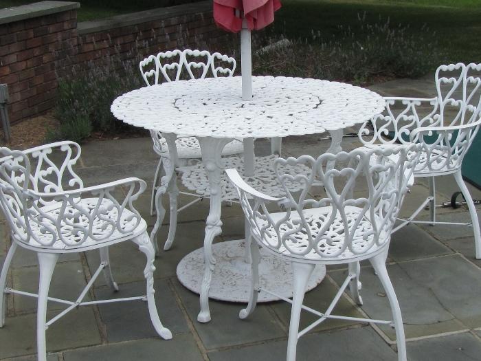 One of three white patio sets, includes umbrella, table and 4 arm chairs