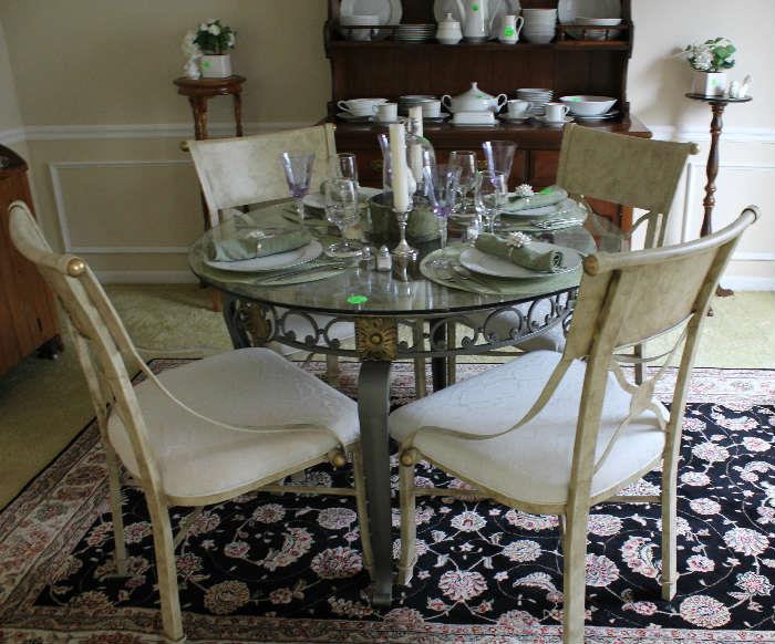 Beautiful round glass top table with 4 metal chairs with white fabric.