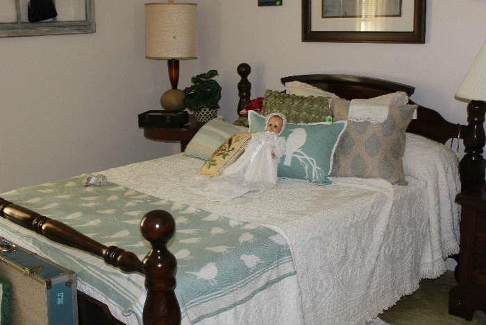 Close-up look of dark pine bed with mattress and box springs with white chenille bed spread.