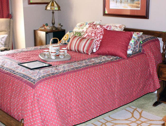 Queen size bed with mattress and box springs with beautiful bed spread, beige tray on bed with  Oriential tea pot and cups.