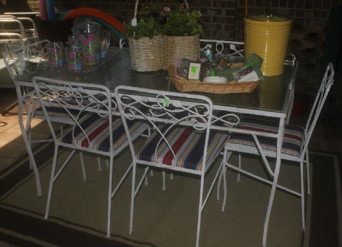 White metal table with glass top and 6 chairs. Has been newly covered.