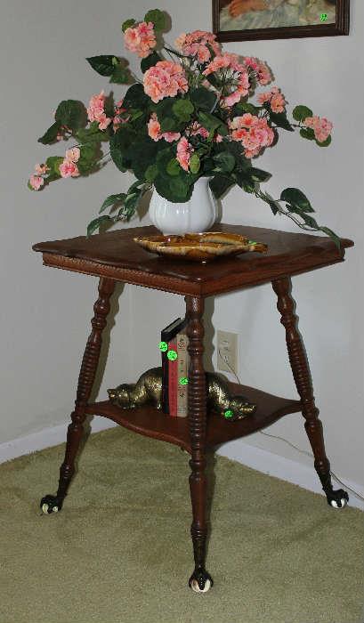 Antique oak table with claw feet and beautiful flower arrangement, books, brass dog bookends on bottom shelf.