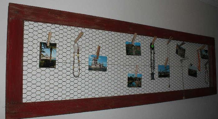 Old screen door with chicken wire hung on wall with post cards and jewelry